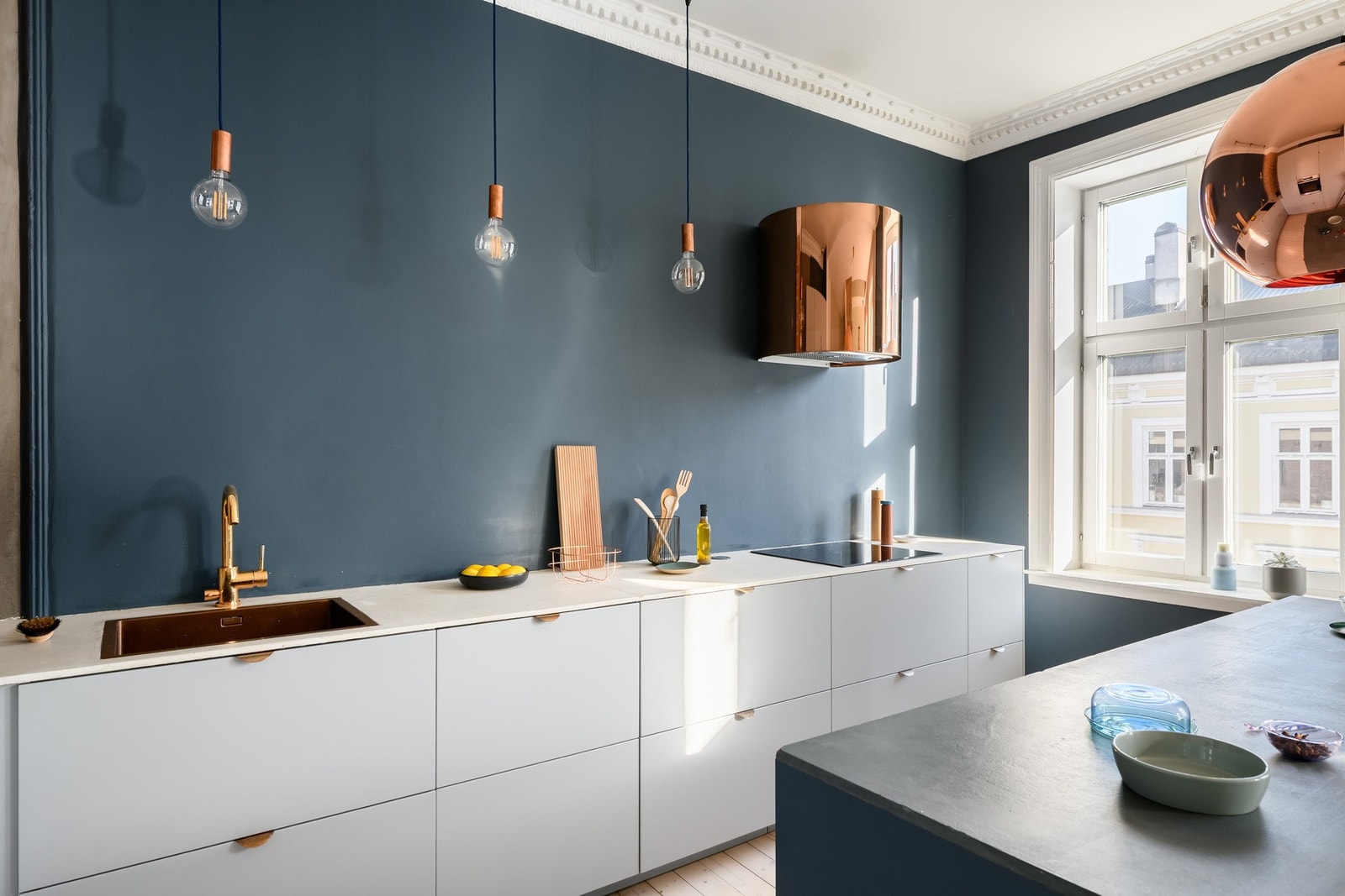 Kobberdetaljene skaper en lekker komplemetærkontrast til den petroleumsblå veggen.
Kjøkkenet har integrerte hvitevarer, benkeplate i laminat, stor kjøkkenøy dekket i mikrosement og god arbeidsflyt. Galleribilde