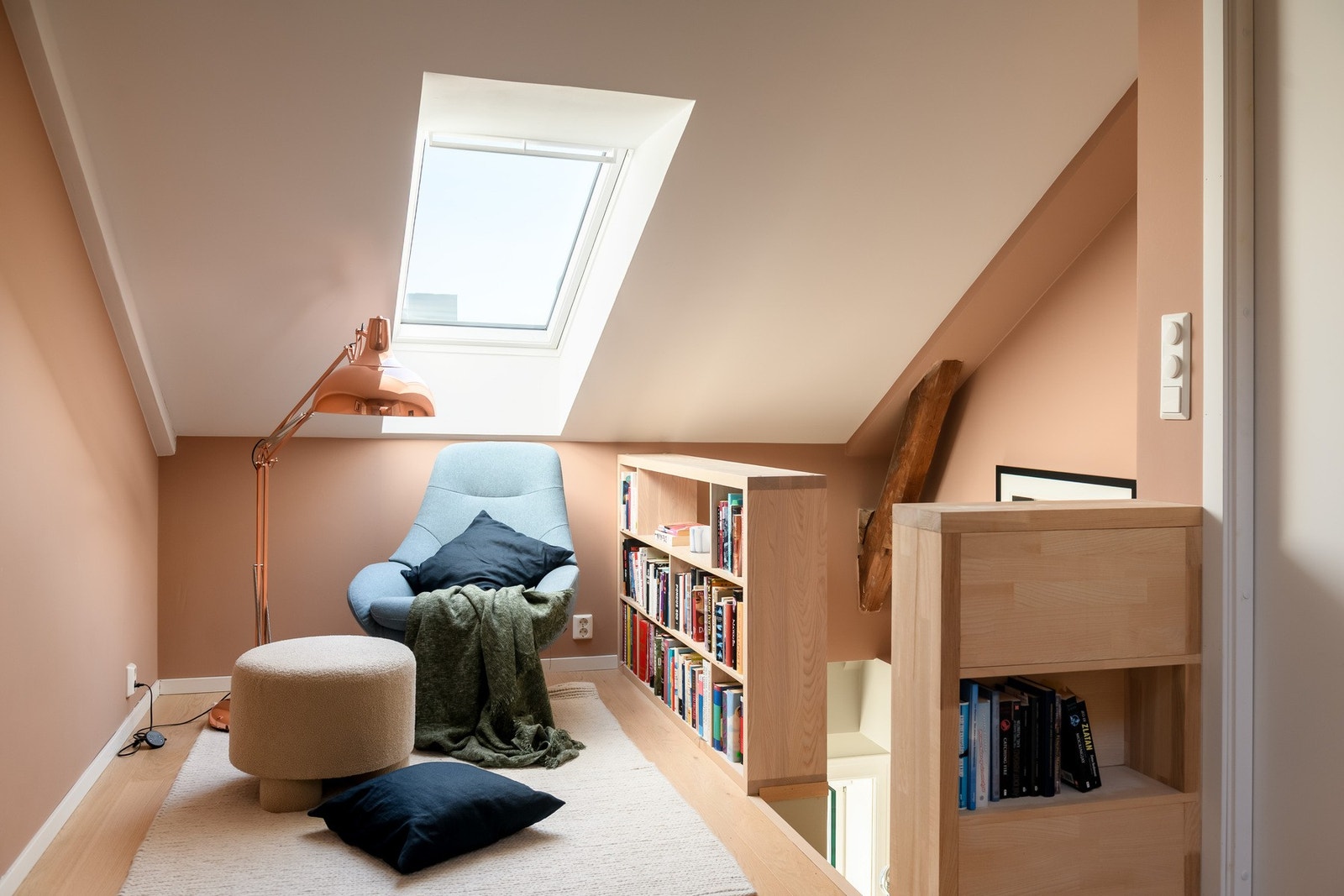 Tosidige bokhyller fungerer som rekkverk og oppbevaring mot trapperommet i den koselige loftstuen. Galleribilde