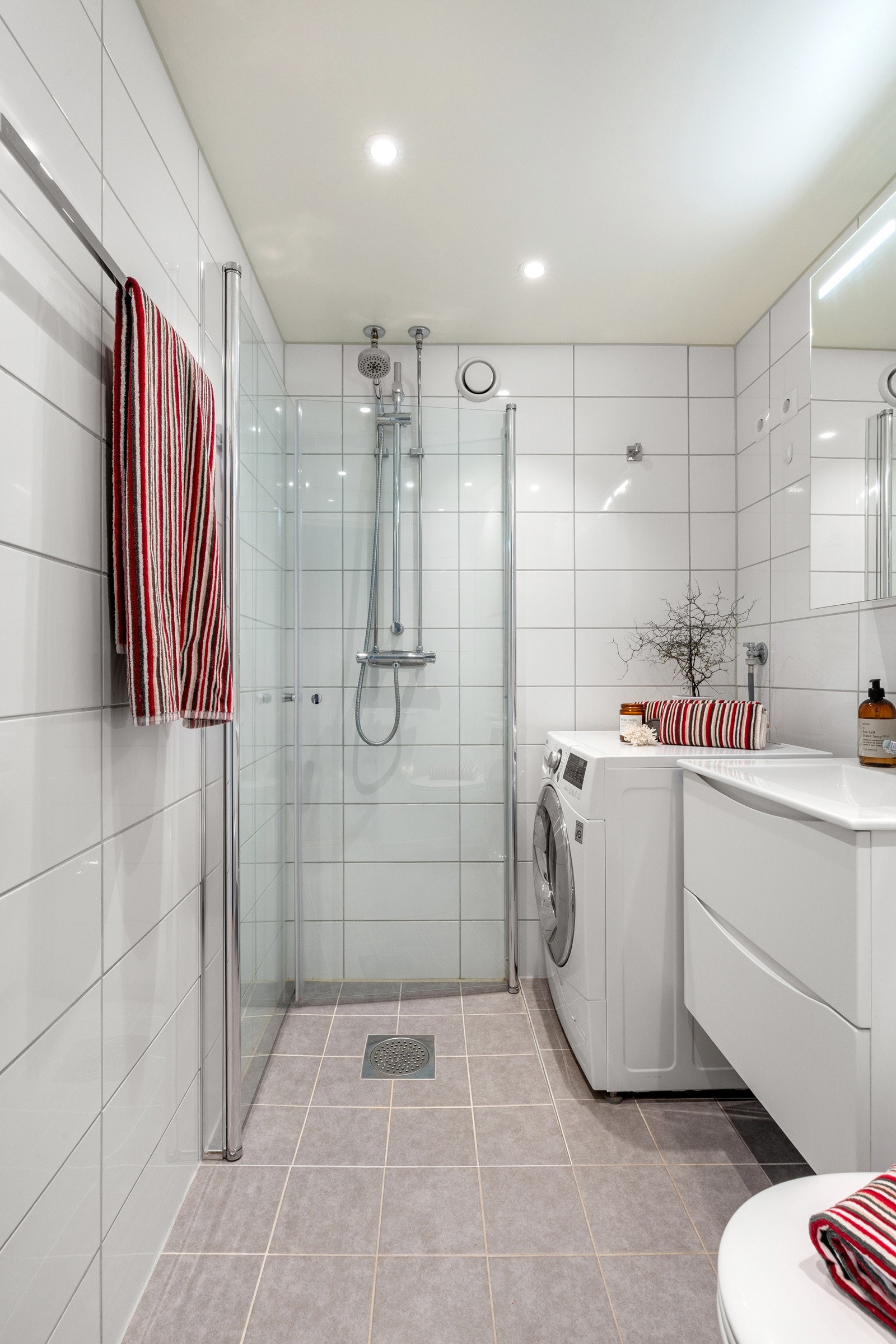 Over servanten er det et speil med integrert belysning. Dusjhjørnet har innfellbare glassdører som gir en romslig følelse når det ikke er i bruk. Galleribilde