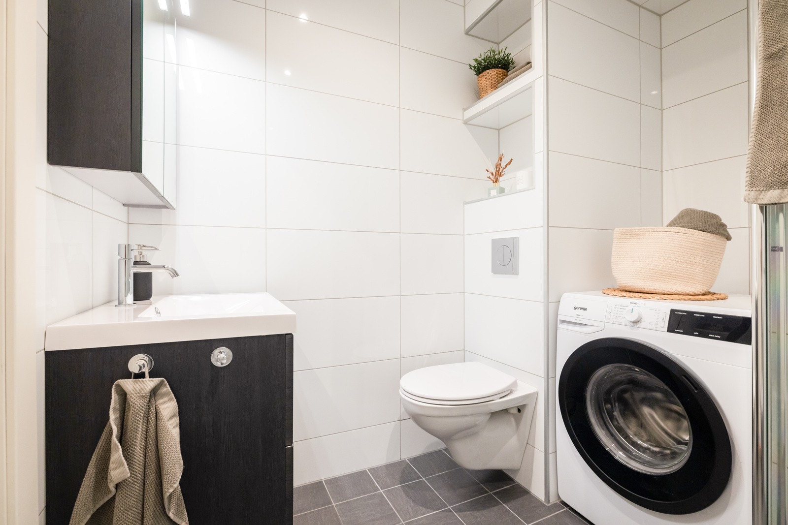 Baderommet inneholder servant med møblement, speilskap med belysning, vegghengt toalett, dusjgarnityr fra 2024, samt innfellbare dusjdødrer av glass. LED-spotlights i himlingen kan dimmes. Galleribilde