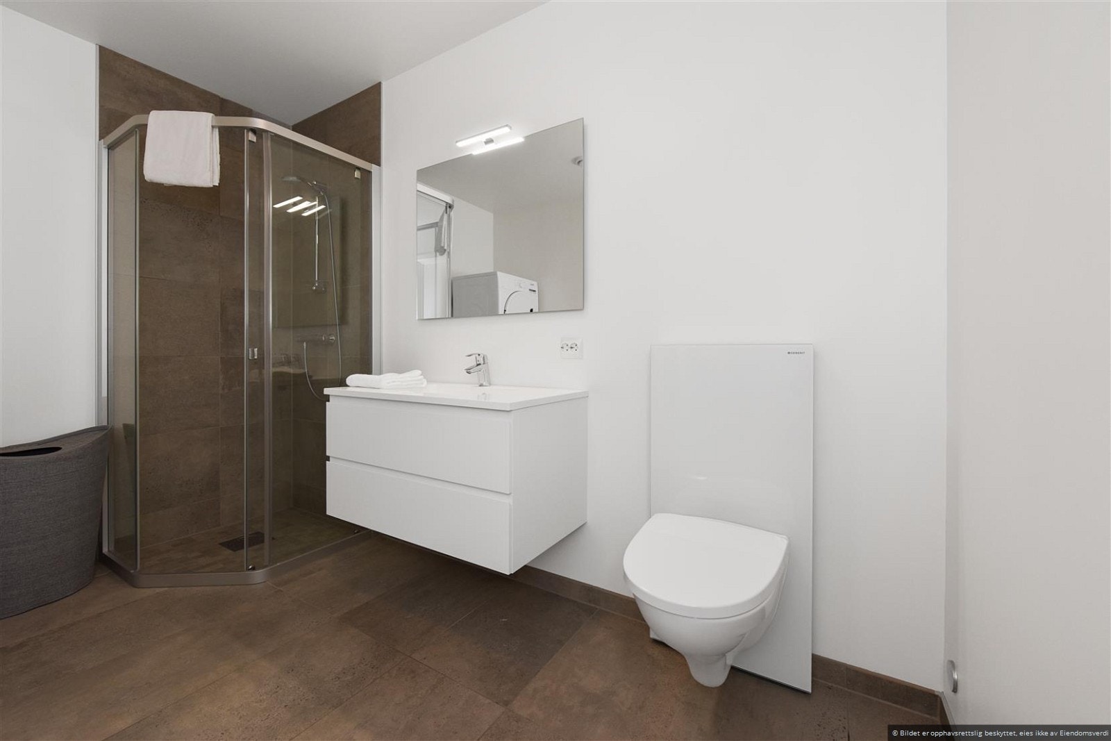 Bade har flislagt gulv med vannbåren varme. Inneholder ellers vegghengt wc, servant med skuffer, dusj og tilkobling til vaskemaskin. Galleribilde