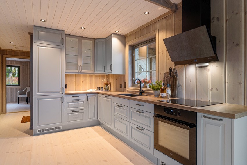 Kjøkkeninnredning fra Epoq med gråmalte profilerte fronter og integrerte hvitevarer som oppvaskmaskin, komfyr, induksjonstopp med ventilator over, kjøl og fryseskap Galleribilde