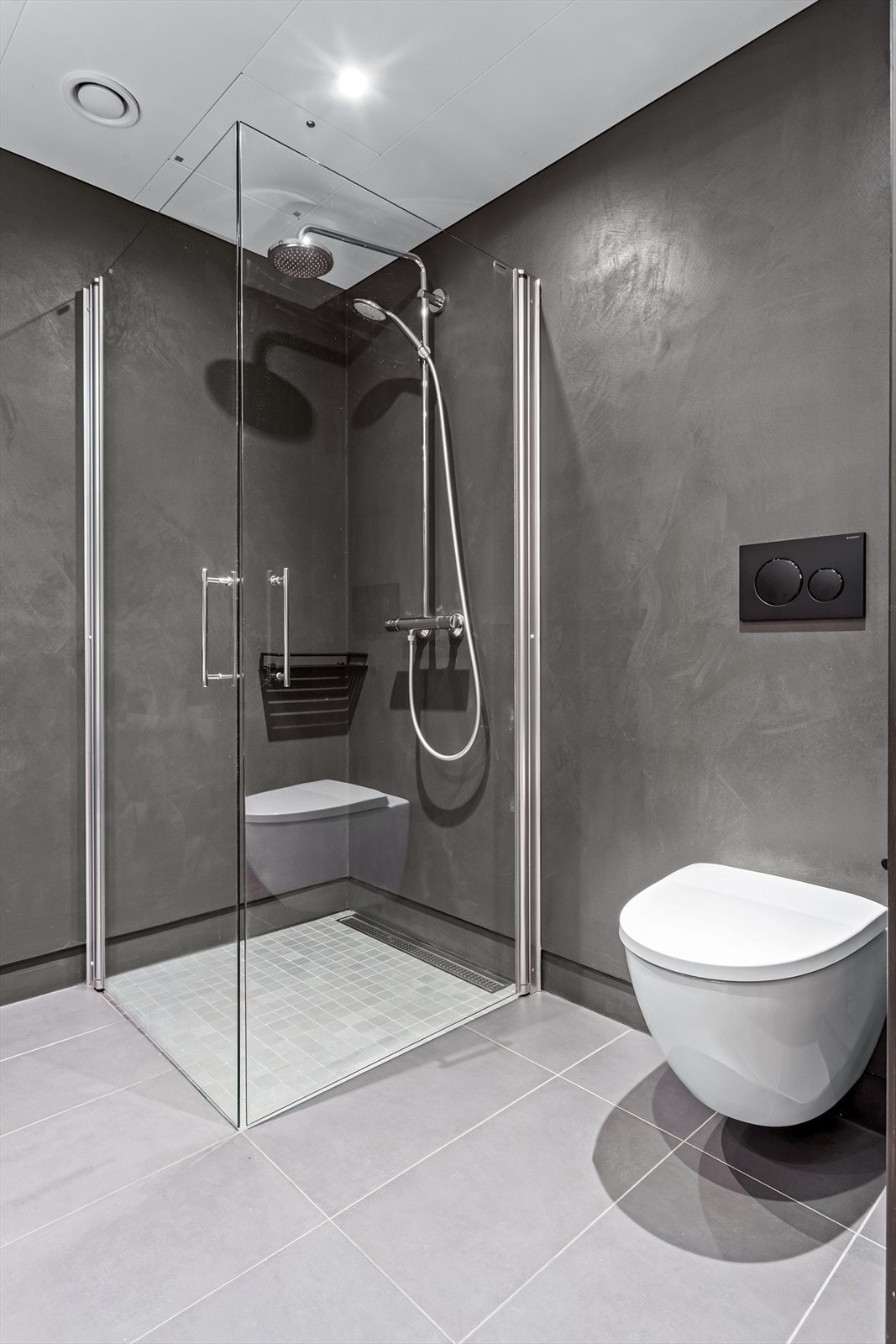 Stor dusj med bl.a hånddusj og fossefalsdusj. Vegghengt klosett Galleribilde