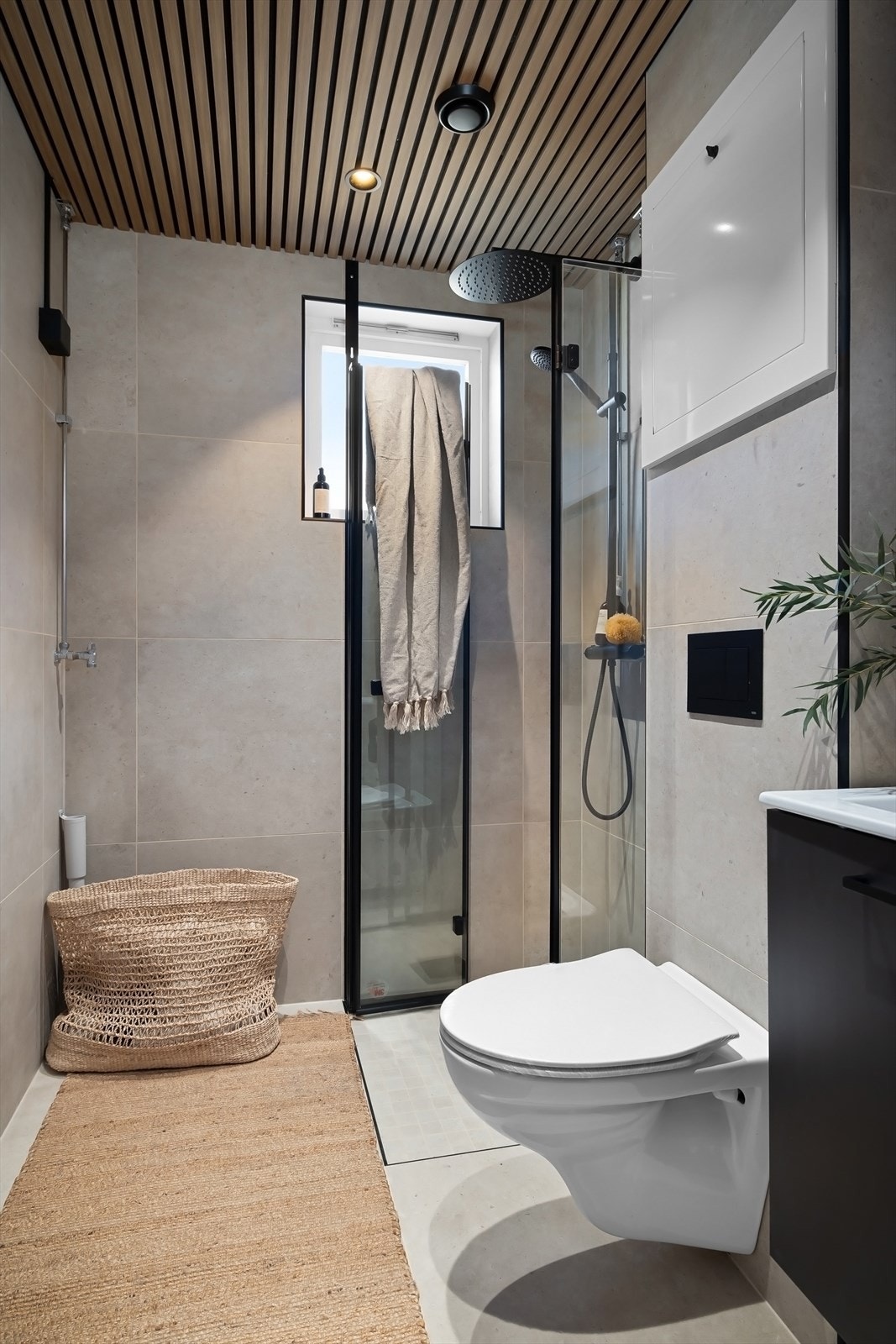 Badet er utstyrt med vegghengt toalett, dusjhjørne med innfellbare glassdører og rainshower samt opplegg for både vaskemaskin og tørketrommel Galleribilde