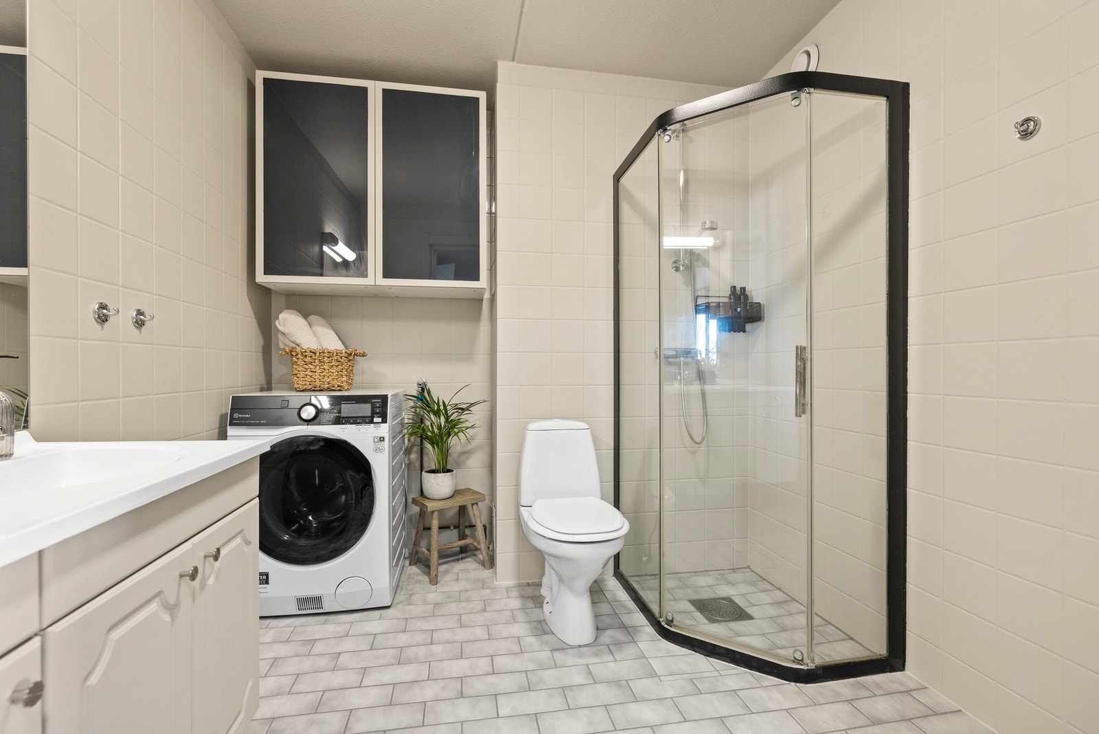 Badet er utstyrt med gulvstående toalett og dusjdører i glass med skyvefunksjon. Galleribilde