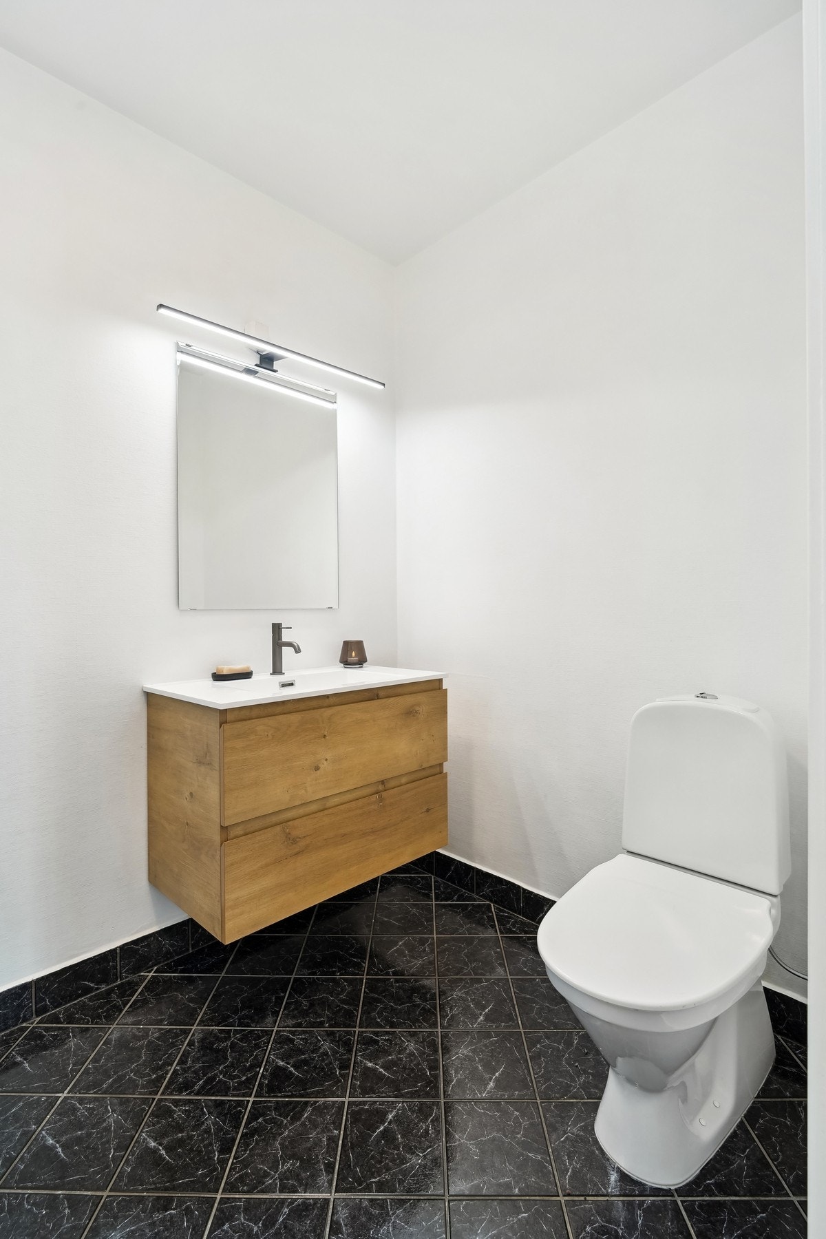 Badet er utstyrt med toalett, servantinnredning med speil og belysning over - Galleribilde