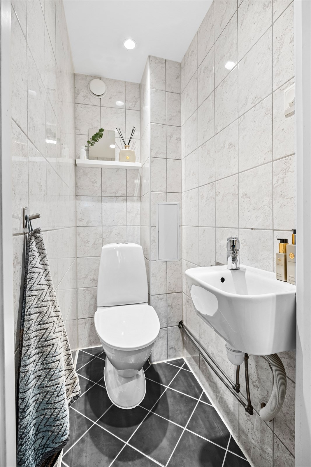 Separat wc-rom med toalett og vask. Flislagte overflater og downlights i himling. Galleribilde