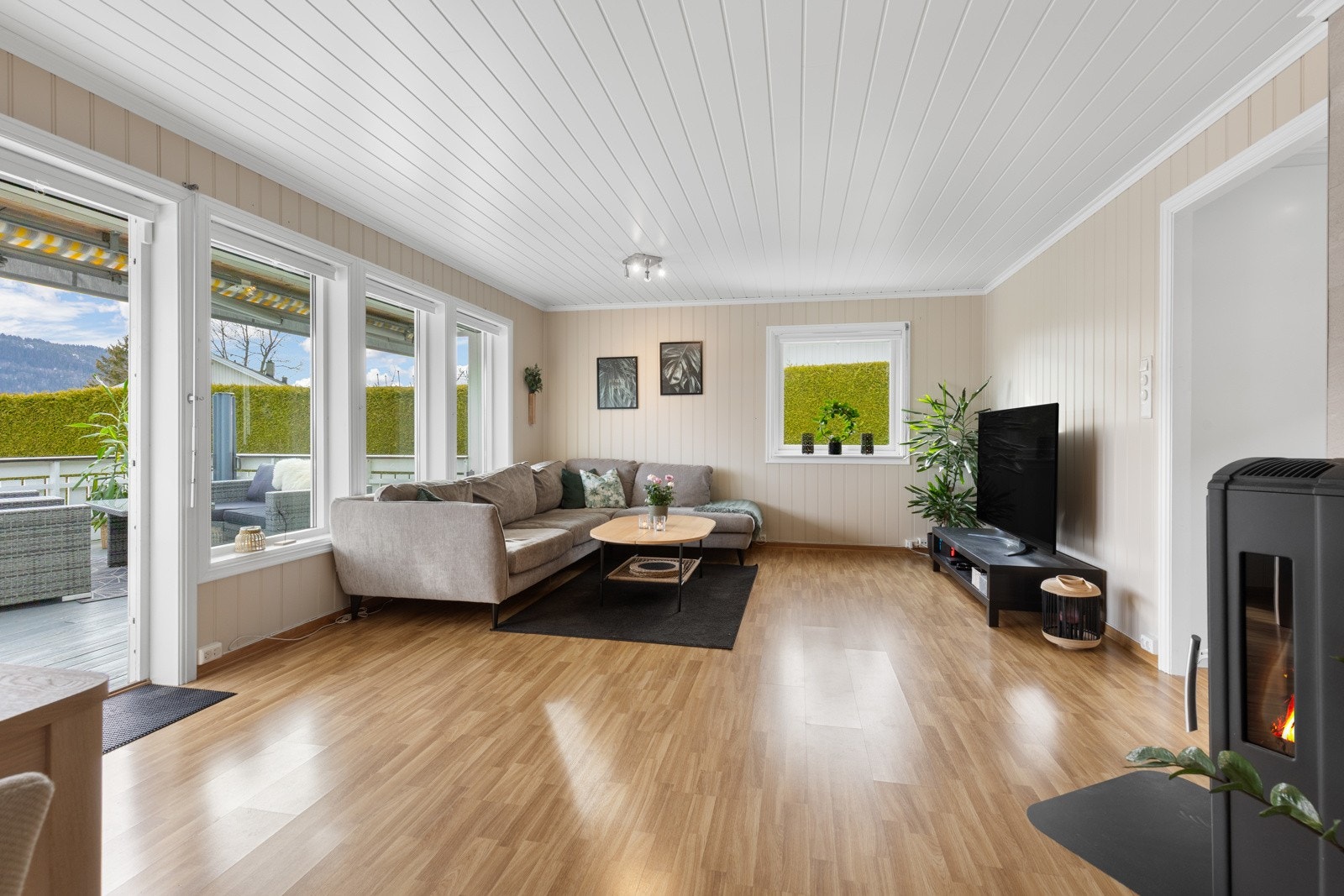 Stor stue med 3-stavs laminat, malt mdf på vegg og malt panel i tak. Galleribilde