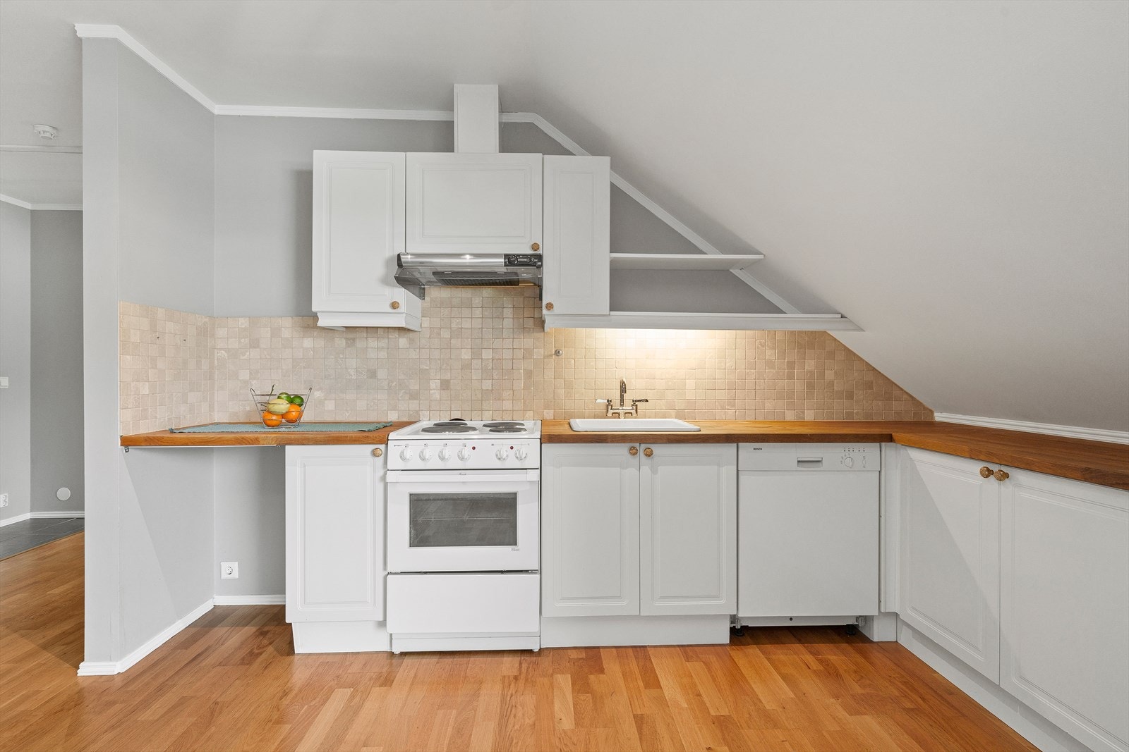 Kjøkkenet har innredning med lyse, profilerte fronter og en benkeplate av heltre, samt at det er avsatt plass til frittstående kjøl/fryseskap, oppvaskmaskin og komfyr. Galleribilde