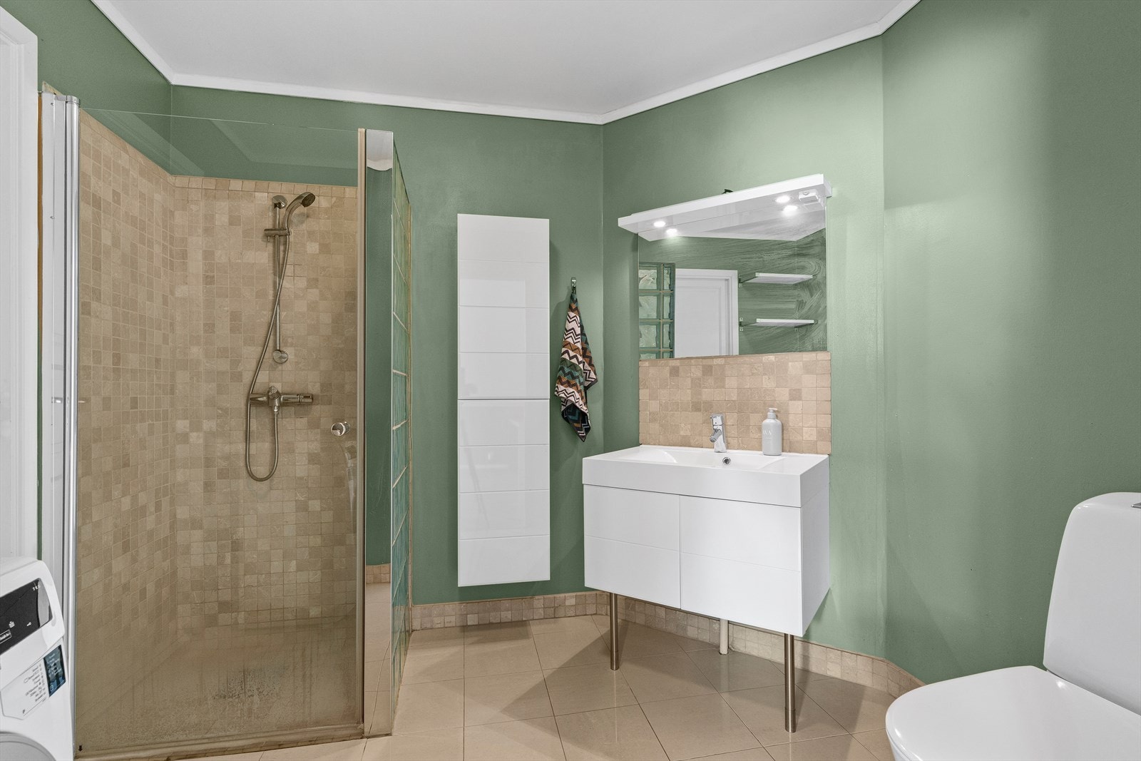 Rommet er er utstyrt med innredning som nedfelt servant, speil med belysning, toalett (nytt i 2018), dusjvegger/hjørne og opplegg for vaskemaskin. Galleribilde