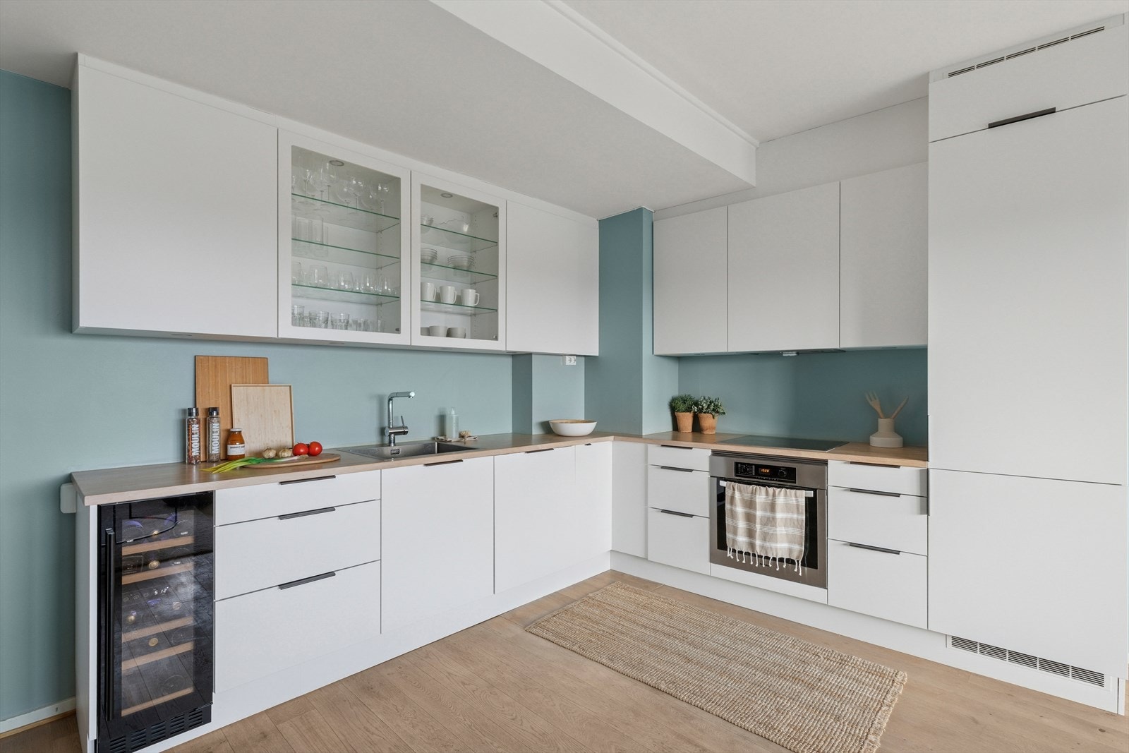 Stilfull kjøkkeninnredning fra HTH som ble satt inn i 2024, som er utført med hvite, glatte fronter. Benkeplaten er i delikat eikeplate. Galleribilde