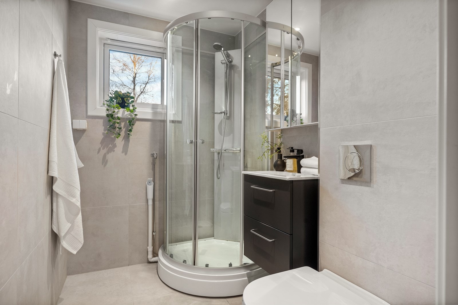 Delikat bad med dusjkabinett, vegghengt wc, servantskap og speilskap. Det er også opplegg for vaskemaskin. Galleribilde