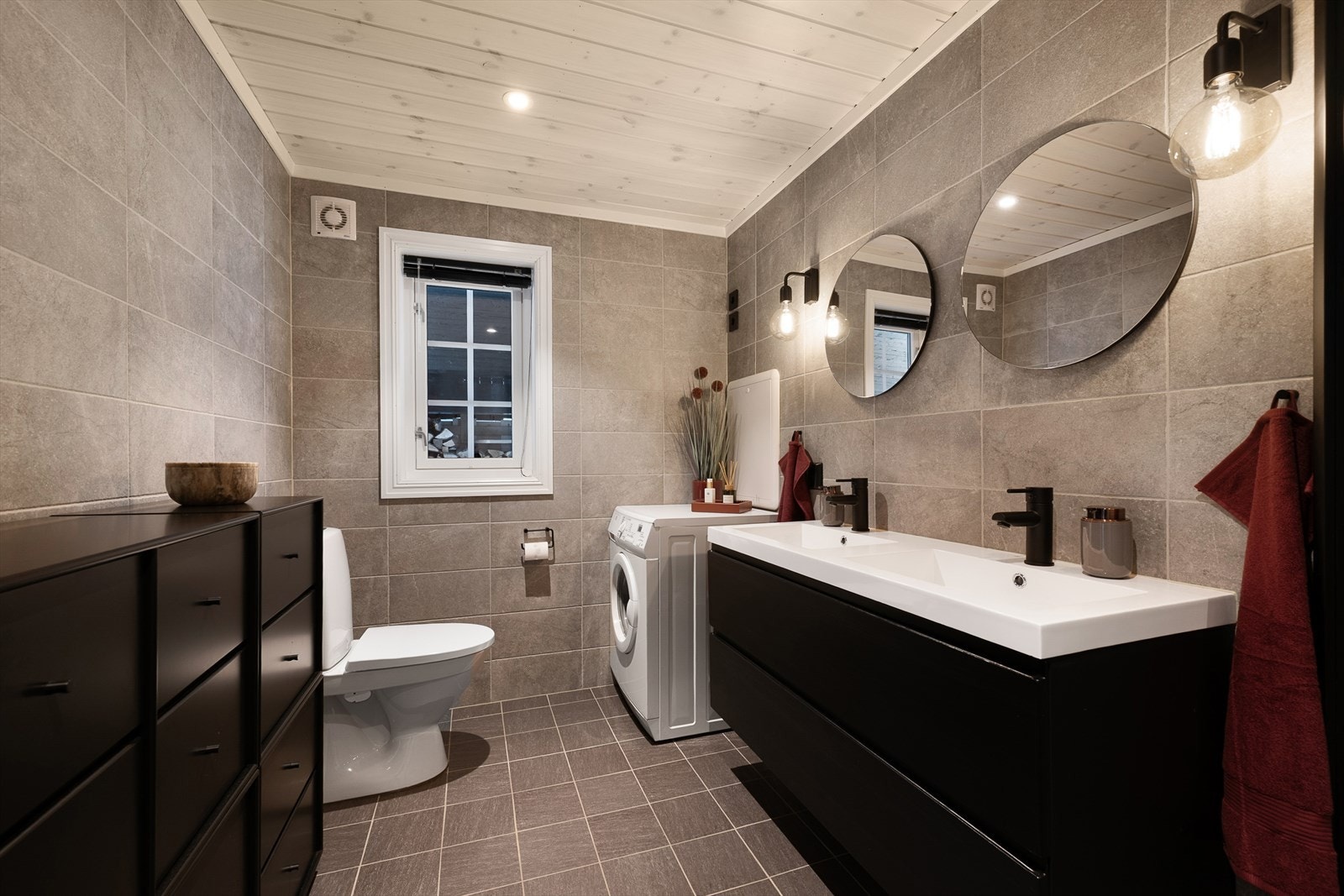 Rommet er innredet med dobbel heldekkende servant med underskap, speil med tilhørende belysning, foldbare dusjvegger, gulvmontert WC og opplegg for vaskemaskin. Galleribilde