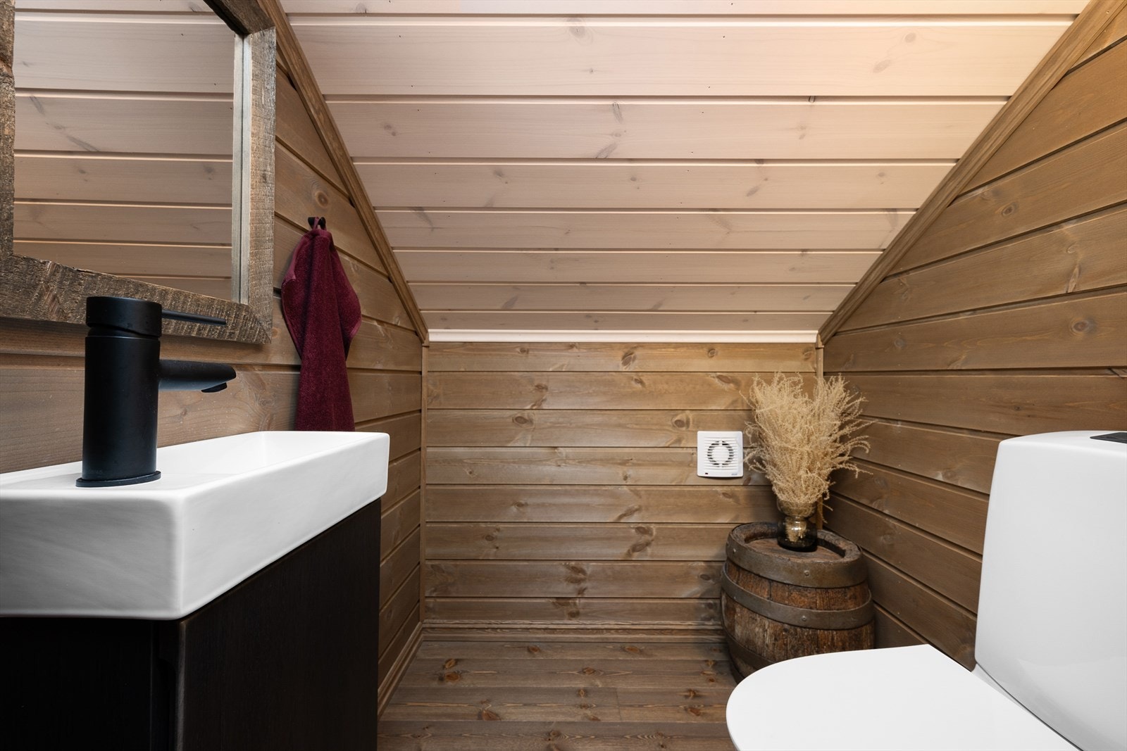 Toalettrommet har heldekkende enkel servant med underskap, speil og gulvmontert WC. Galleribilde