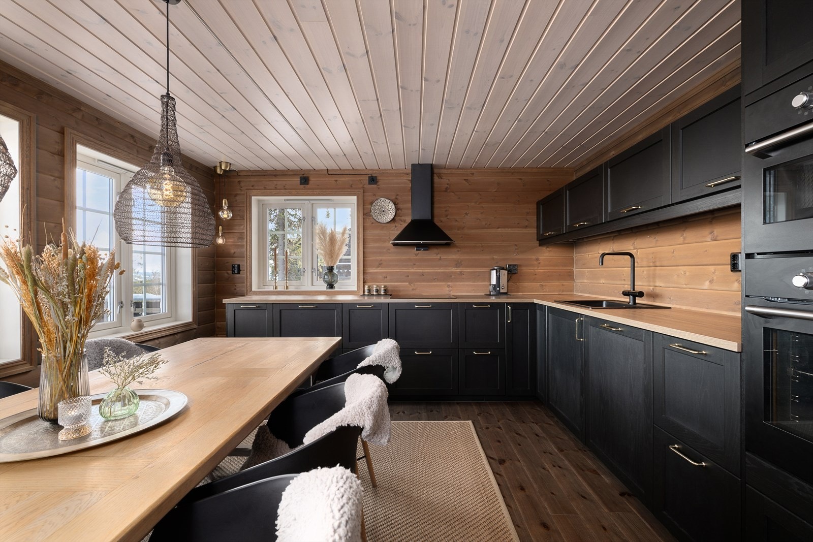 Det moderne kjøkkenet har innredning med laminerte skrog, sorte profilerte fronter og laminert benkeplate med kjøkkenkum. Galleribilde