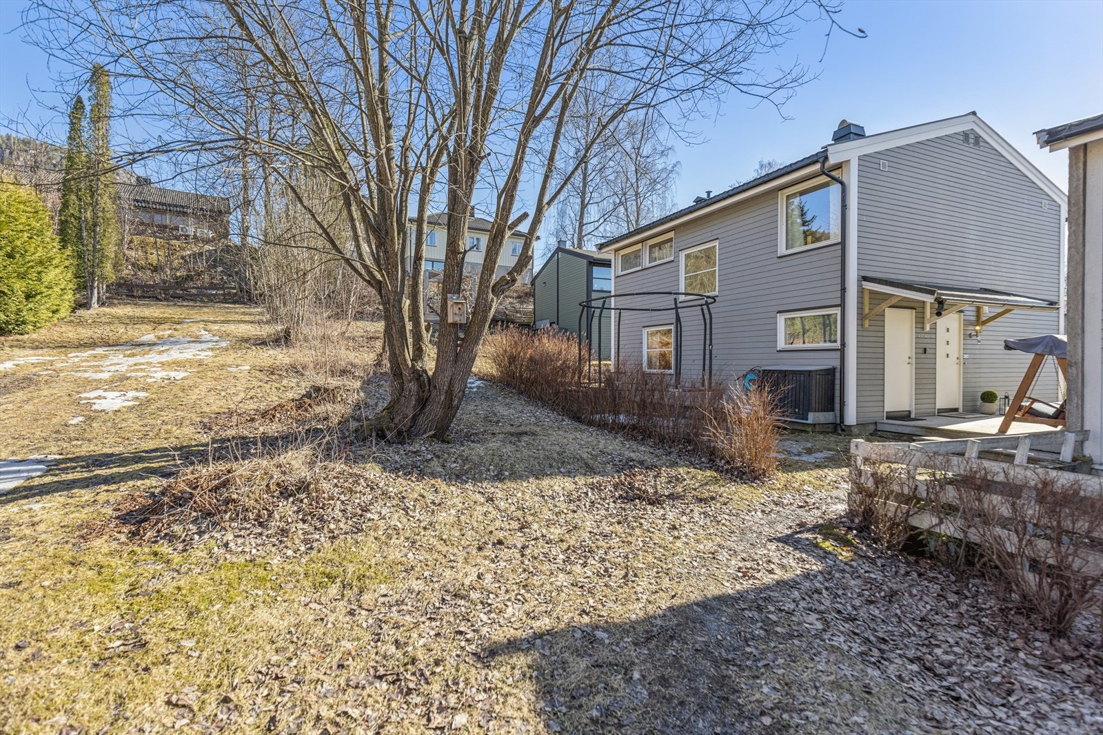 Baksiden av boligen vender ut mot stort friareale som benyttes som grendas akebakke om vinteren Galleribilde