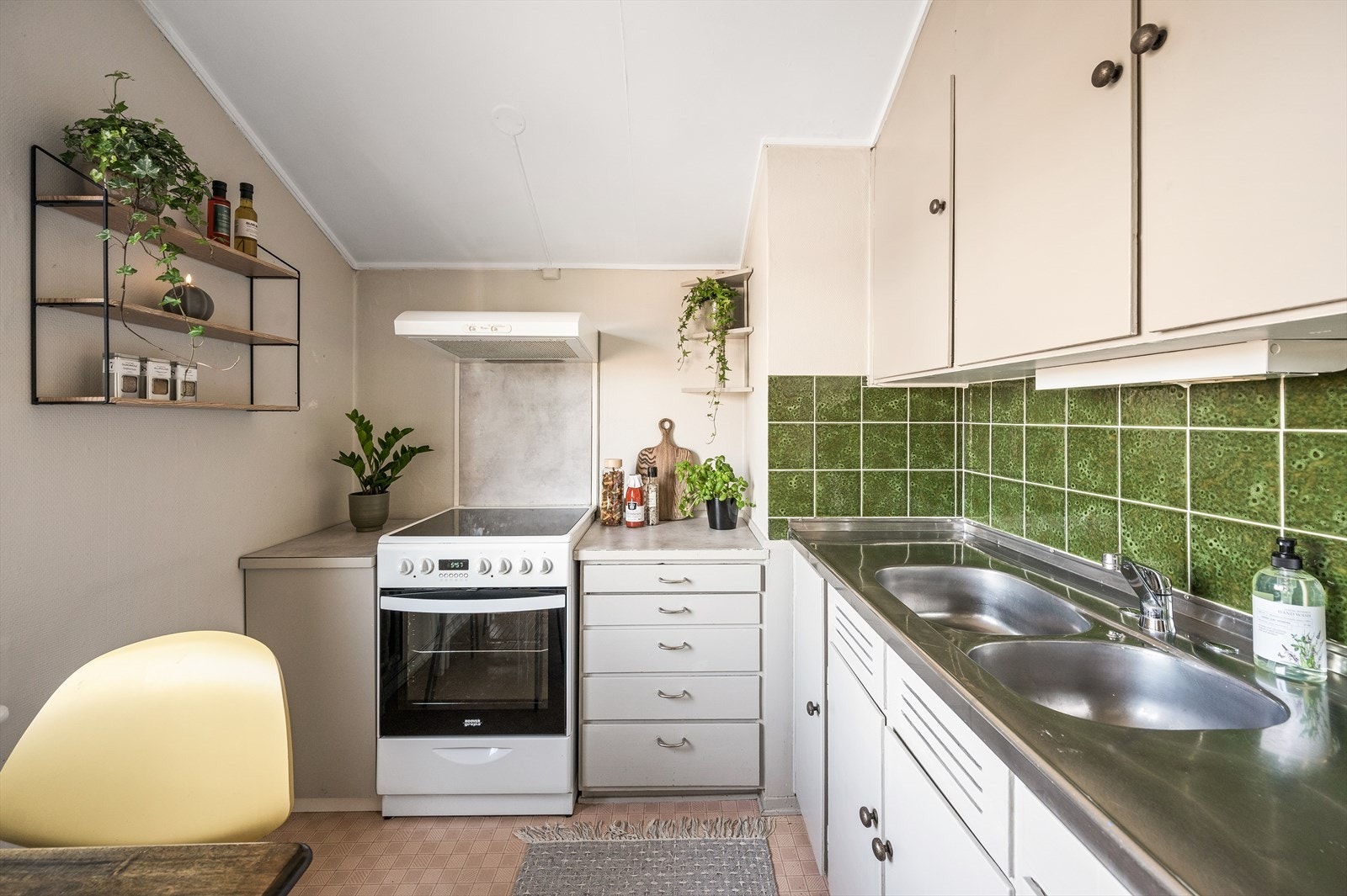 Kjøkkeninnredning antatt fra byggår med glatte fronter og pålimt laminat benkeplater med integrert oppvaskkum. Galleribilde