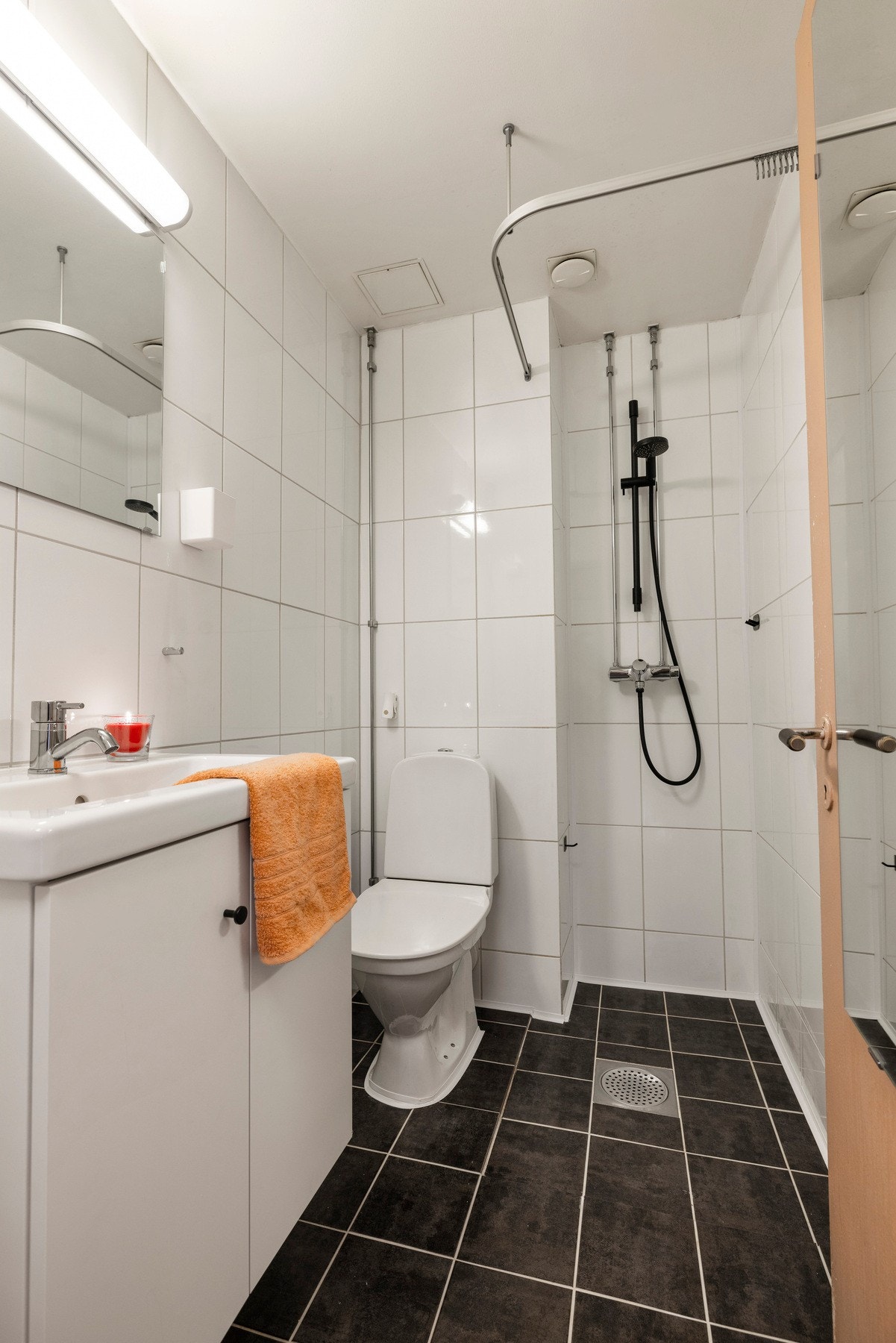 Baderommet har et innbydende og tidløst design med flislagte gulver og vegger som gir et fresht og lettstelt inntrykk. Innredningen består av vegghengt heldekkende servant (satt inn 2025) med et praktisk speil med overlys og stikkontakt over, dusjnisje me Galleribilde