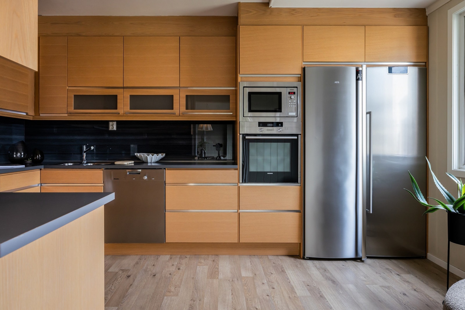 Kjøkkenet er av god størrelse. Mellom kjøkkenbenk og overskap er det glassplate. Nedfelt oppvaskkum med ett-greps kjøkkenarmatur. Praktisk med benkeskapsbelysning og stikkontakter over kjøkkenbenken. Galleribilde