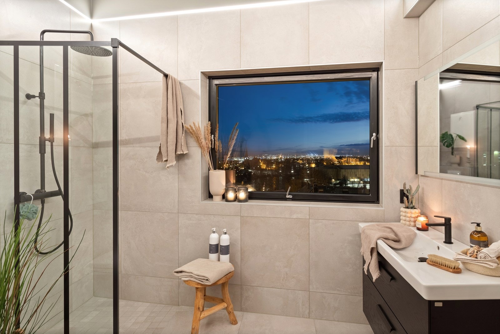 Pent flislagt baderom med moderne og stilren innredning. Her er det etablert servant med servantskap, dusjhjørne, opplegg for vaskemaskin og vegghengt
toalett. Galleribilde