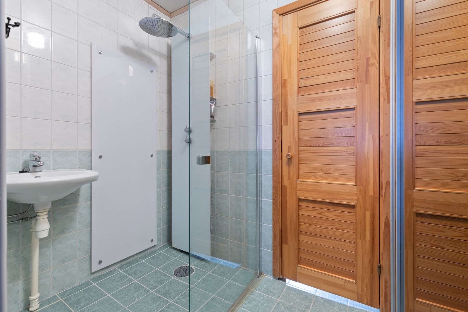 Vaskerommet har fliser på gulv med gulvvarme og tapetserte veggflater i kombinasjon med fliser ved dusjløsning. Galleribilde