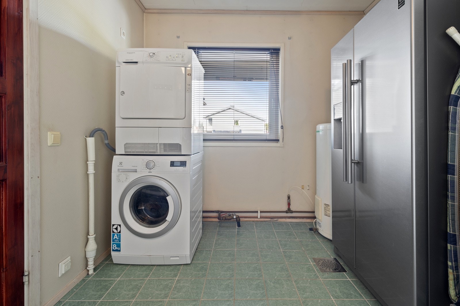 Familievennlig vaskerom med standard fra byggeår. Inneholder bla. enkel servant, dusjsone med regnfallsdusj, garderobeskap, samt opplegg for både vaskemaskin og tørketrommel. Boligens varmtvannsbereder er plassert her. Galleribilde