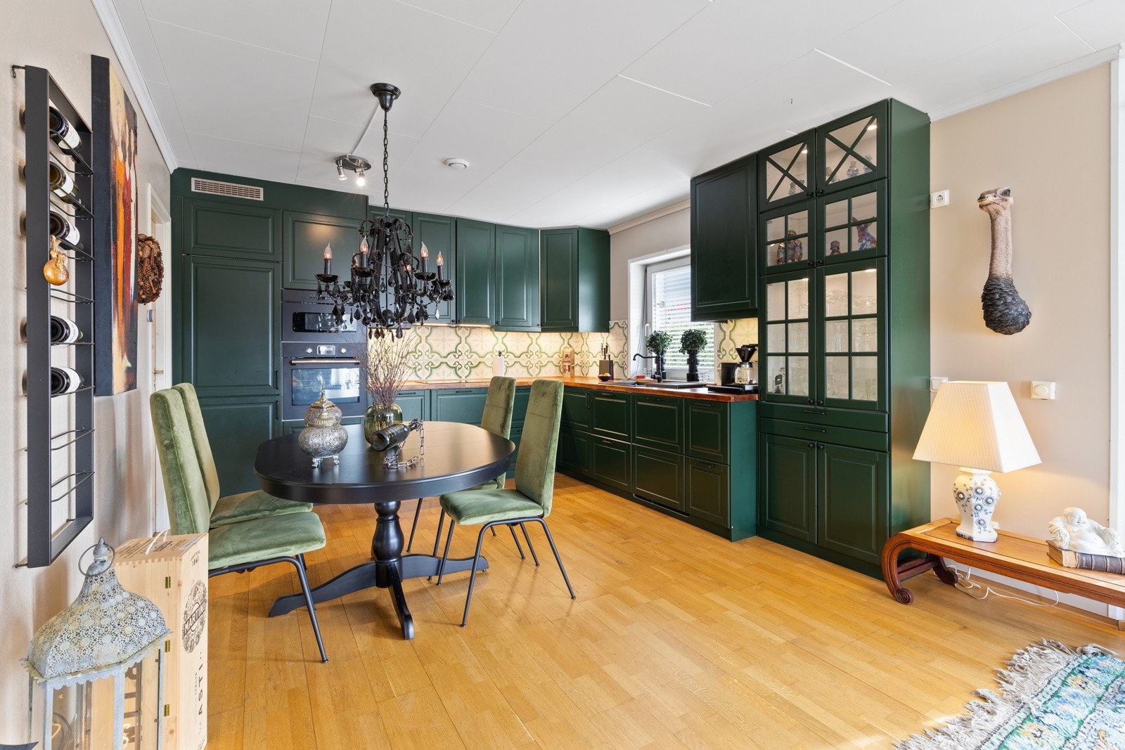 Pent klassisk kjøkken av god størrelse - utformet i vinkel for maksimal utnyttelse av rommet. Innredning med malte profilerte fronter med foring opp til tak i kombinasjon med opplyste vitrineskap. Benkeplate i heltre med nedfelt vaskekum. Galleribilde