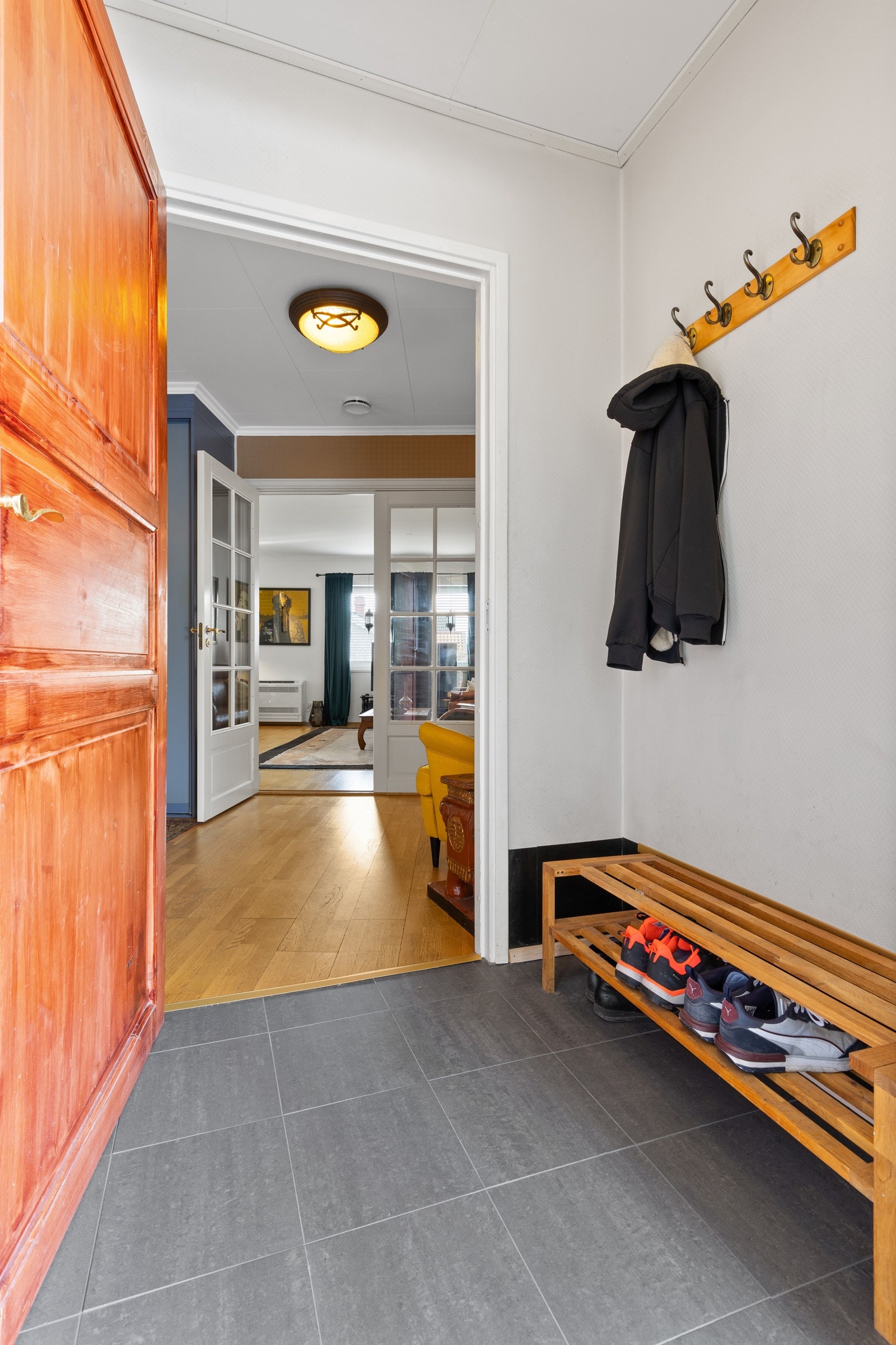 Entre med fliser på gulv med gulvvarme og lysmalte veggflater. Galleribilde