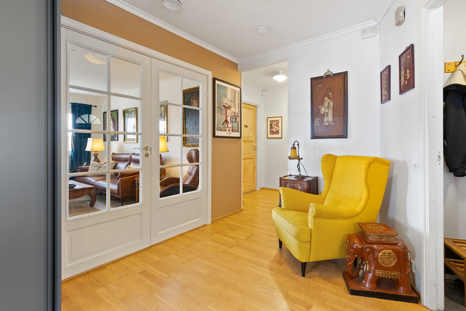 Tiltalende gang med parkett på gulv og lyse veggflater. De doble sprossede dørene fører inn til stuen og kjøkkenet. Galleribilde