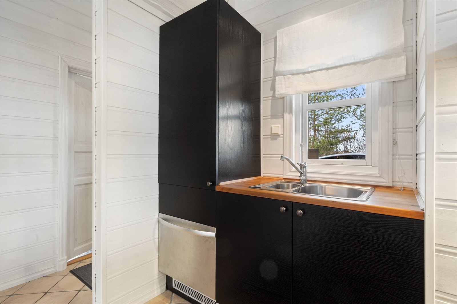 Oppvaskbenk foran vinduet, og integrert kjøleskap og oppvaskmaskin. Galleribilde