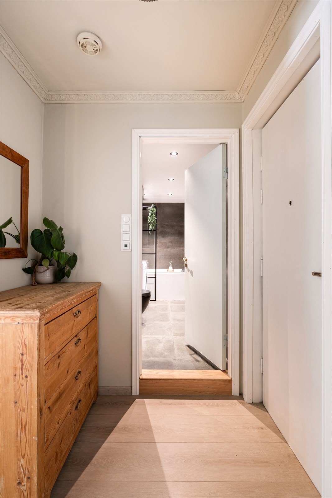 Mellom døren til badet og stuen er det plass til en kommode for oppbevaring av luer, skjerf og annen bekledning. Galleribilde