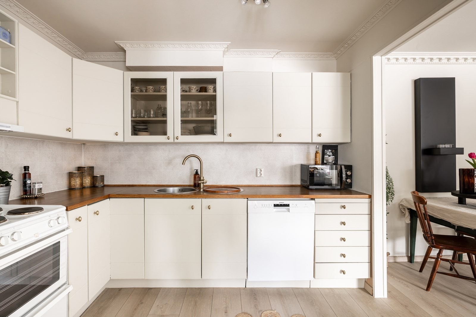 Pent kjøkken oppgradert med fronter som ble pusset og malt i 2021 i fargen "soft white". Det er nyere kjøkkenkran i stiling farge som passer godt til håndtakene på frontene. Galleribilde