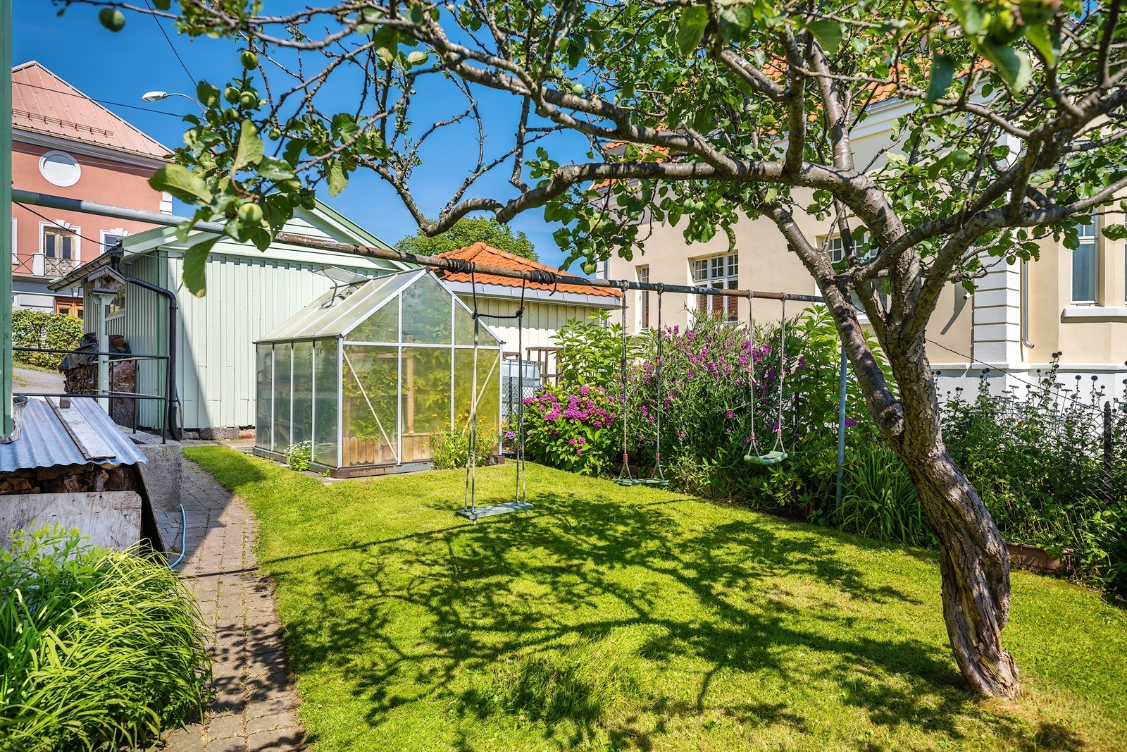 Sjarmerende og idyllisk hage med frukttrær, drivhus og beplantninger av ulike slag. Galleribilde