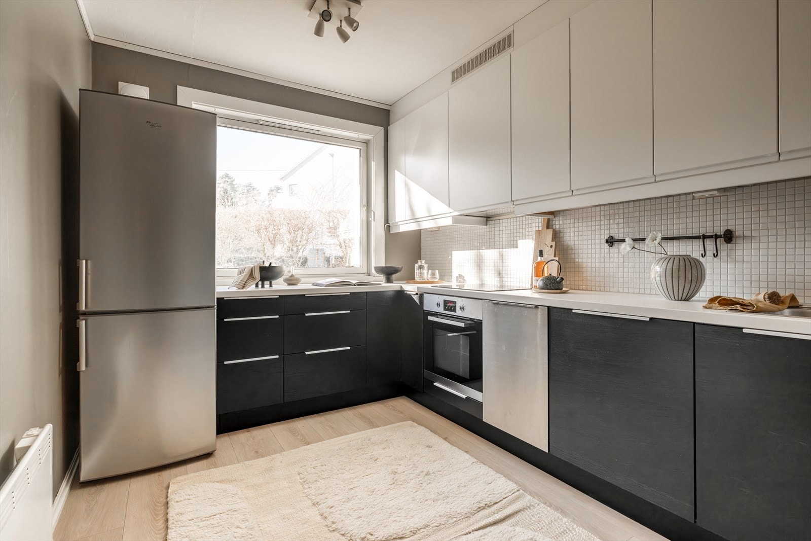 Leiligheten har et separat kjøkken med plass til lite spisebord. Tidløs kjøkkeninnredning fra IKEA (2011) med laminerte benkeplater, flislagt backsplash og slette skapfronter. Galleribilde