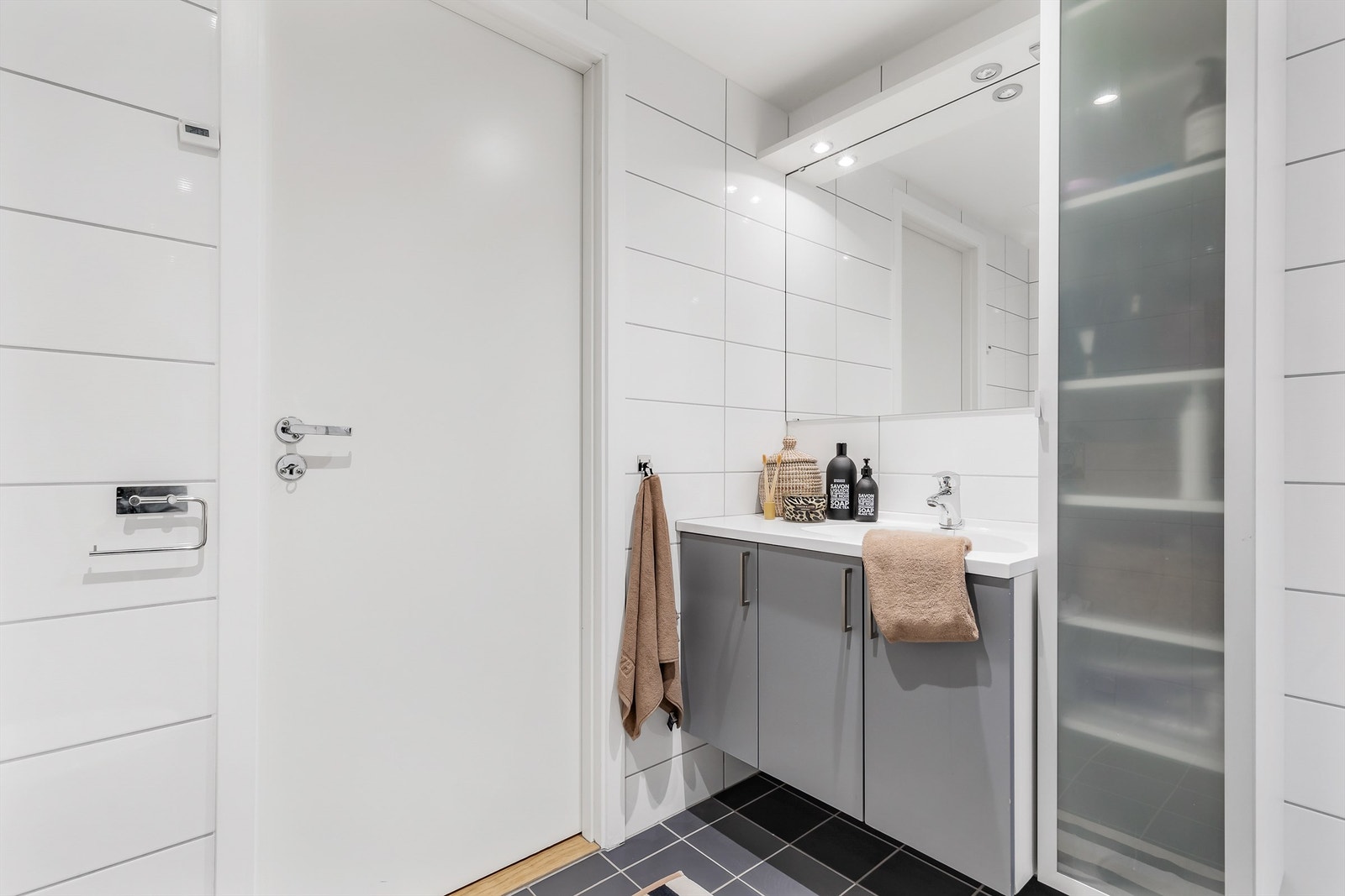 Vegghengt servantskap med ovenpåliggende servant og ett-greps armatur. Speil, belysning og stikkontakt over servant. Vegghengt høyskap. Galleribilde