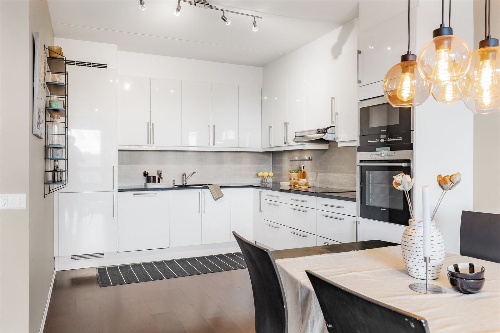 Overbelysning og stikkontakter over benk. Integrerte hvitevarer. Kjøleskap med fryser, oppvaskmaskin, stekeovn, mikrobølgeovn og platetopp. Vegghengt ventilator. Galleribilde