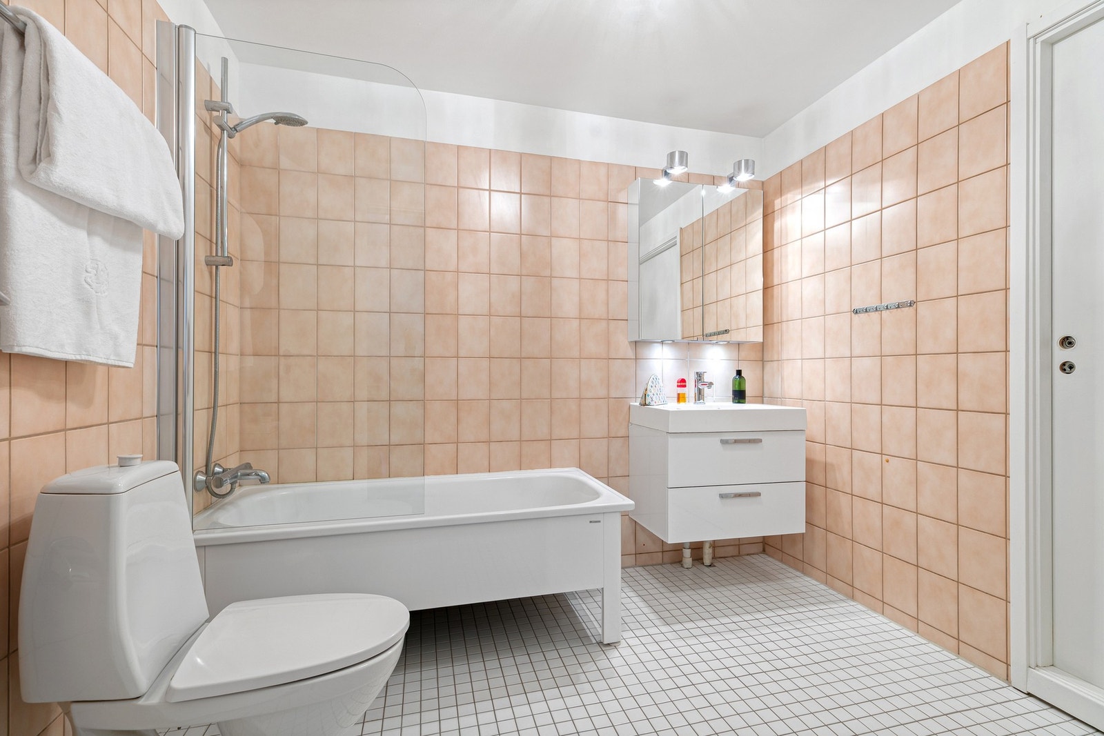 Bad med toalett, servant med skuffeseksjon, speilskap, vegghengt skap og et frittstående badekar. Galleribilde