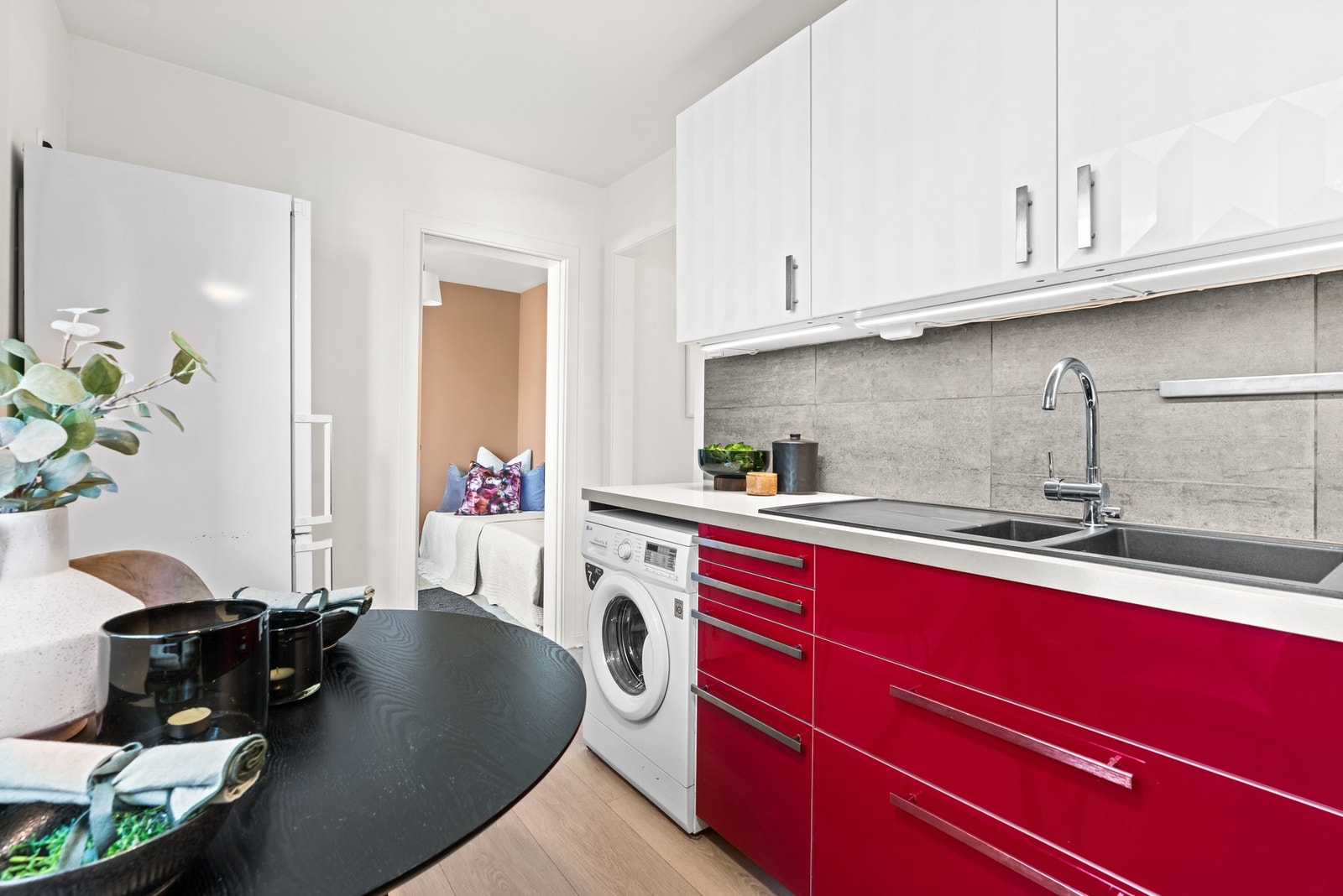 Videre har kjøkkenet integrert koketopp og stekeovn, samt en kullfilterventilator over kokesonen. Det er også opplegg for vaskemaskin under kjøkkenbenken, og plass til frittstående kjøleskap. Galleribilde