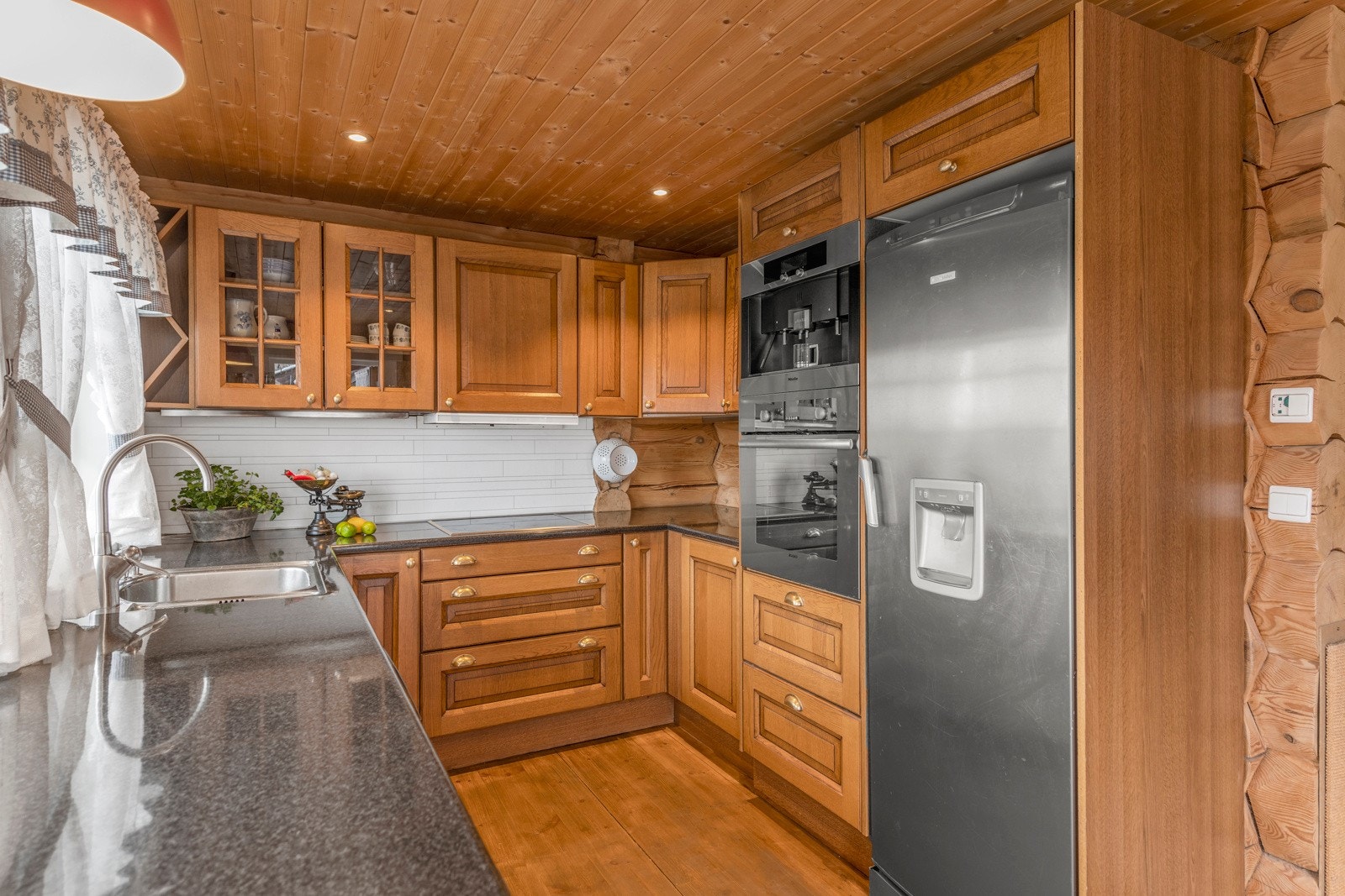 Pent kjøkken med innredning med heltre fronter i profilert utførelse og laminat benkeplate. Galleribilde