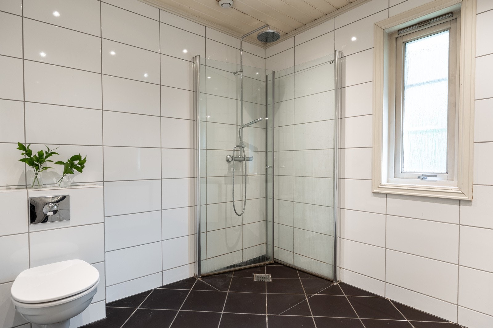 For øvrig dusjhjørne med glassdører, regnfalldusj og to-greps armatur, samt vegghengt toalett med innebygget sisterne. Galleribilde