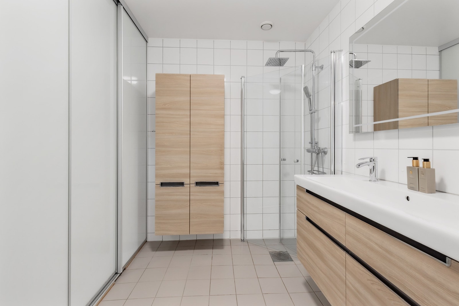 Badet er innredet med vegghengt klosett, dobbel servant med innredning og dusjhjørne med svingbare glassdører. Galleribilde