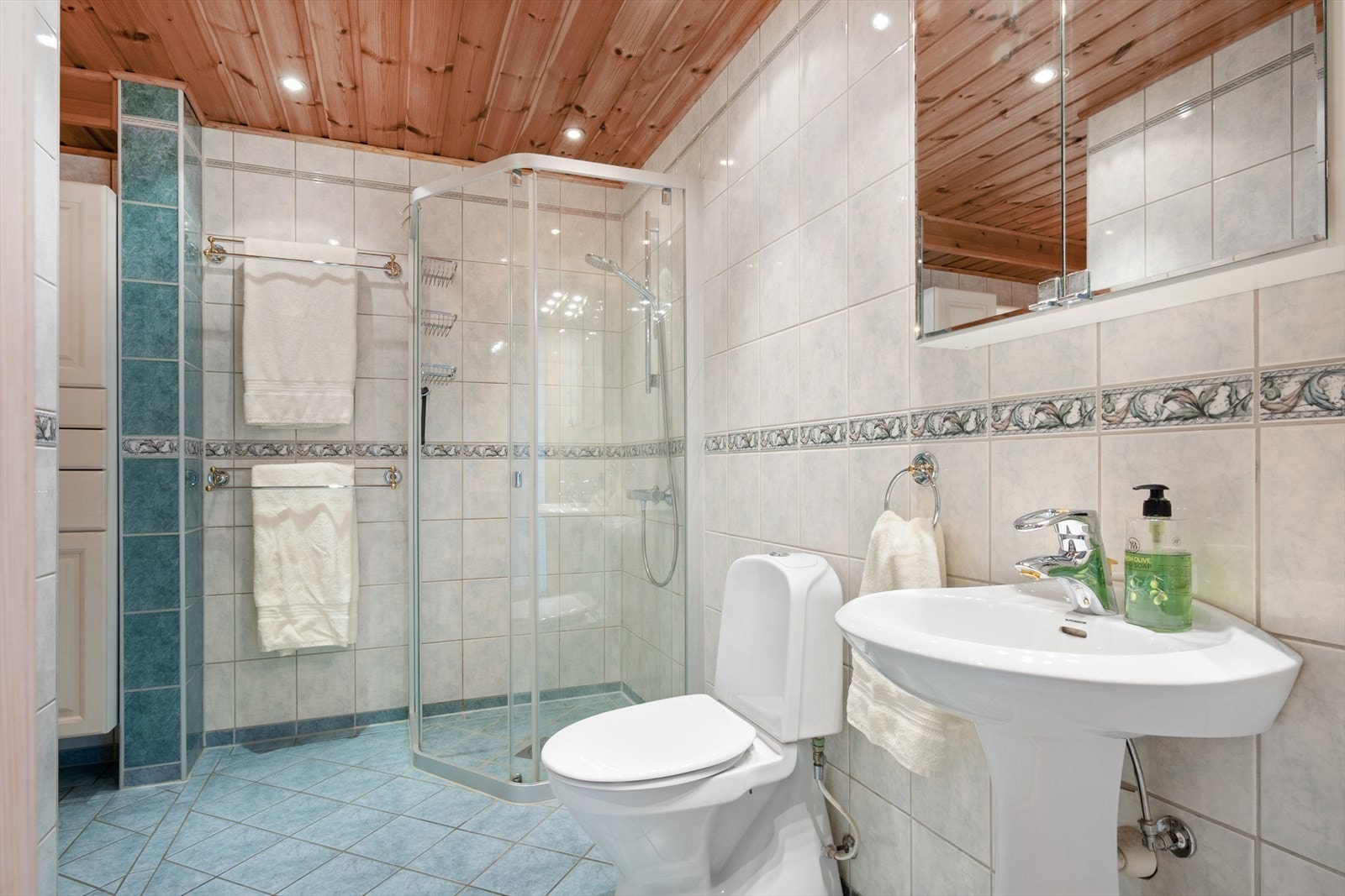 Badet i underetasje fremstår romslig med flislagte overflater, gulvvarme og downlights. Innredet med blant annet dusjhjørne og to vasker. Galleribilde