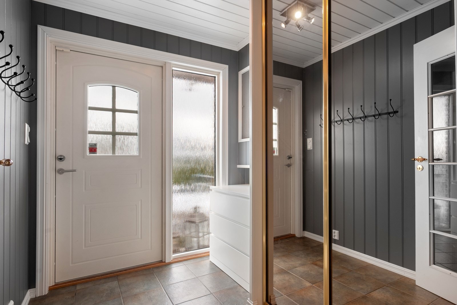 Entreen har flislagt gulv, skyvedørsgarderobe, knaggrekke og plass til oppbevaringsmøbel. Galleribilde