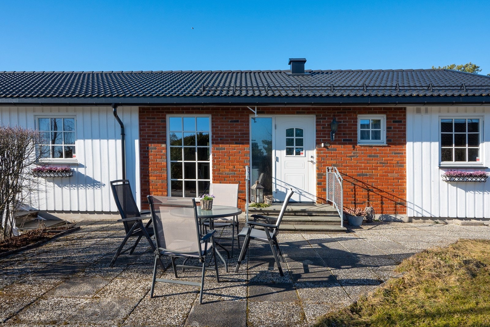 Ved inngangspartiet har eiendommen en hellelagt, skjermet uteplass med mulighet for sittegruppe eller spisebord. Galleribilde