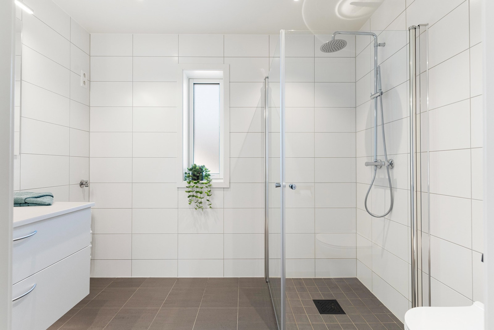 Badet er lyst og pent med elektriske varmekabler i gulvet. Opplegg til vaskemaskin til høyre for vasken. Galleribilde