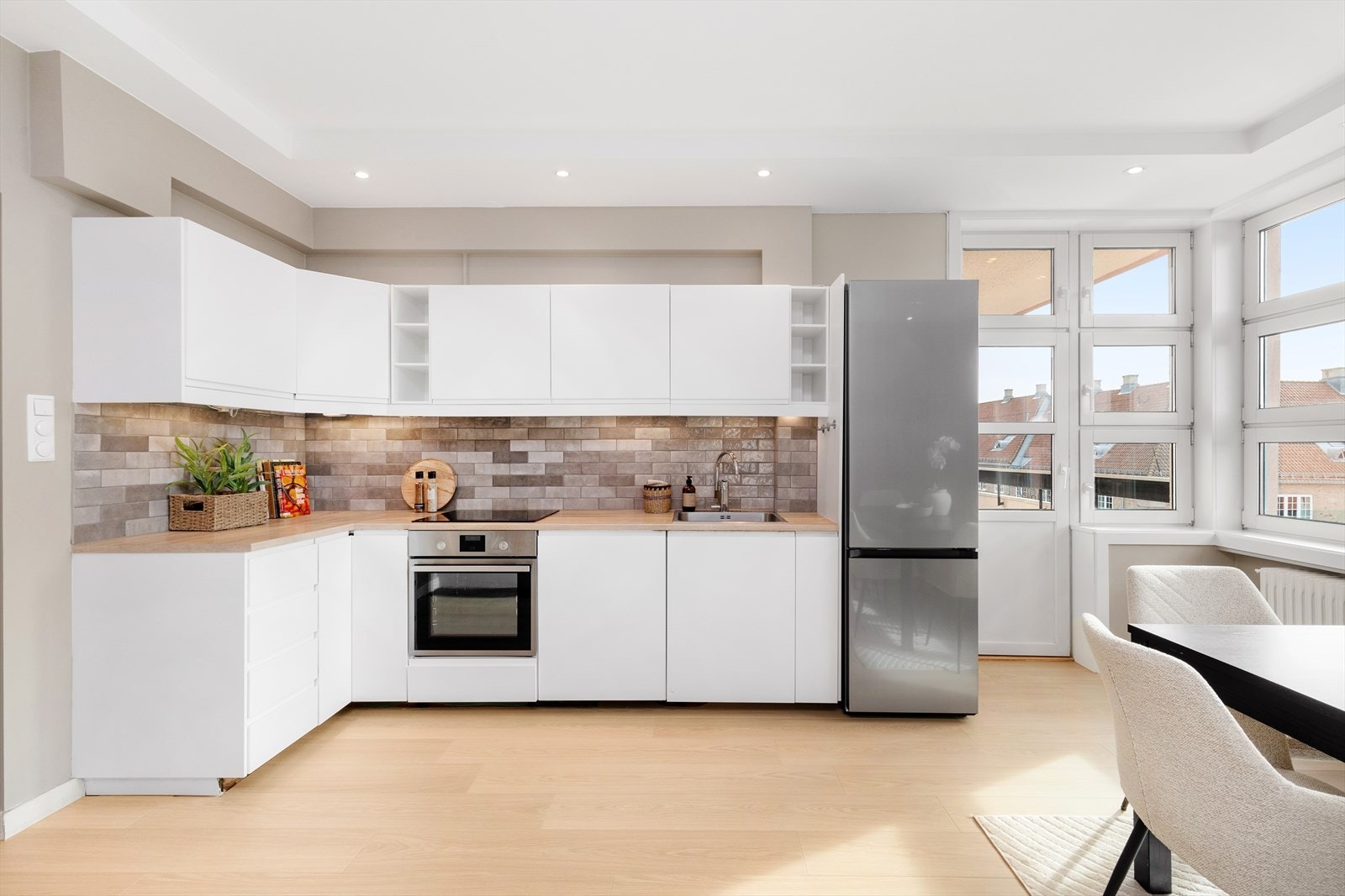 Kjøkken med malte glatte fronter og benkeplate med nedfeldt vaskekum og keramisk platetopp. Galleribilde