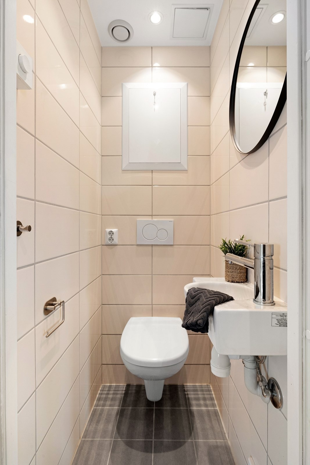 Separat toalettrom med flislagt gulv og vegger. Utstyrt med servant, og vegghengt toalett. Galleribilde