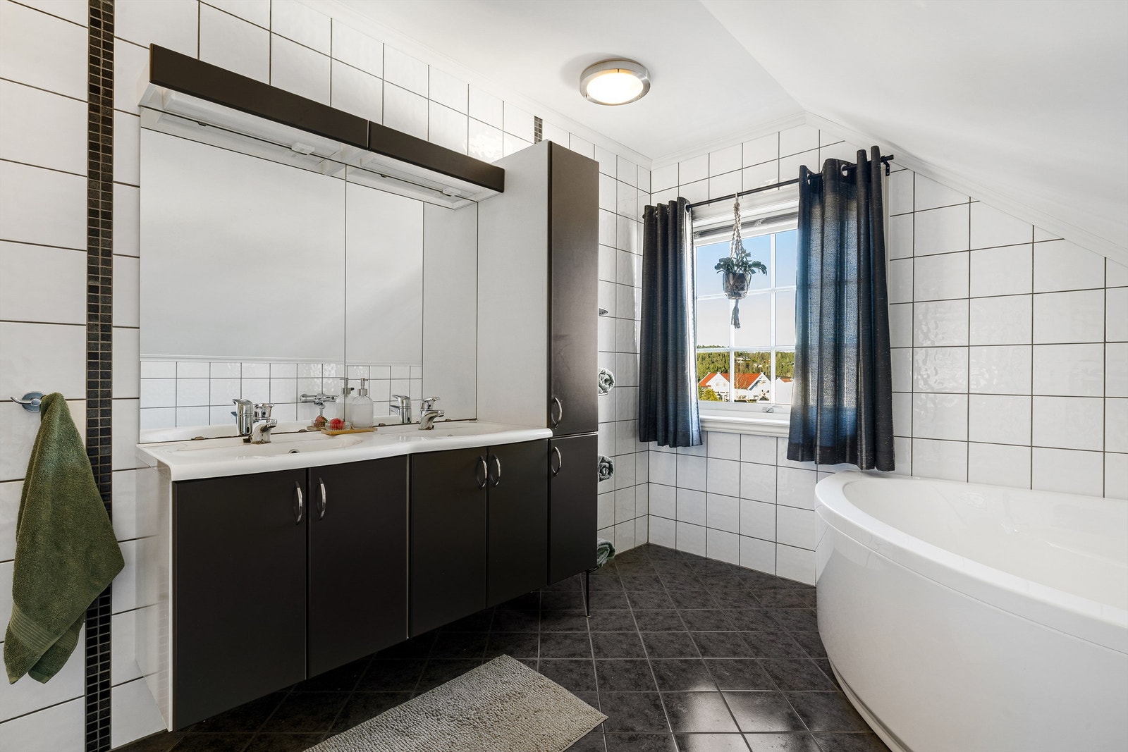 Delikat flislagt bad med dobbel servant i innredning, badekar, dusjnisje og wc. Galleribilde