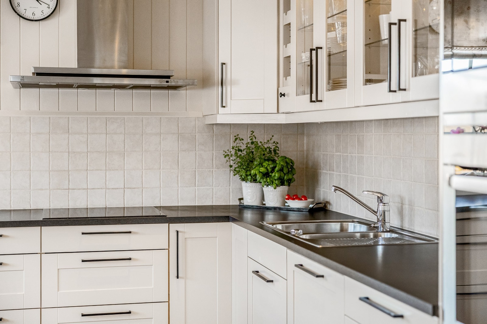 Lyse profilerte fronter, laminat benkeplate og fliser mellom over-/underskap. Galleribilde