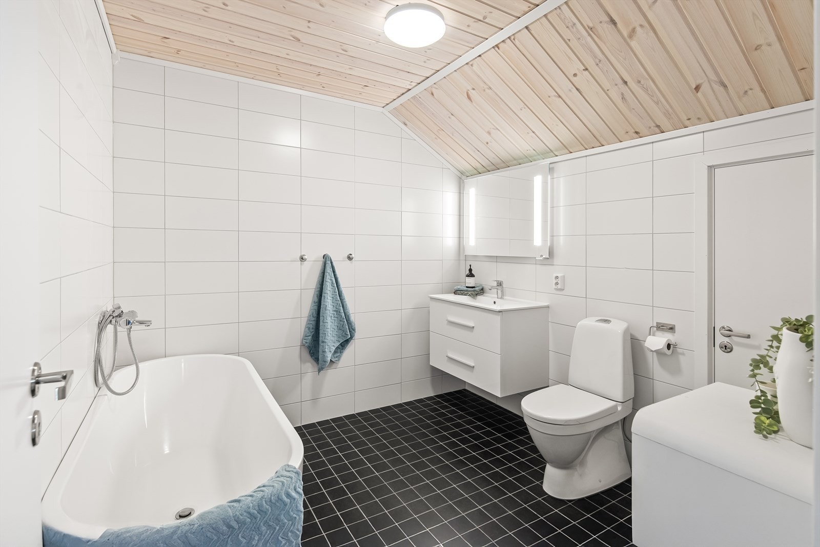 Badet på andre plan er utstyrt med baderomsinnredning med heldekkende servantbenk nedfelt i innredning med skuffer og overhengende speil. Videre er det toalett og badekar med dusjarmatur. Galleribilde